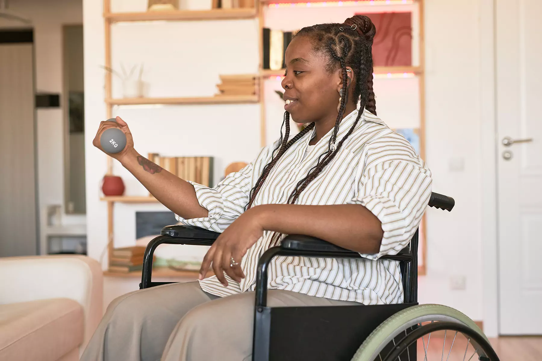 A disabled woman sitting in her wheelchair while holding a 2kg dumbbell